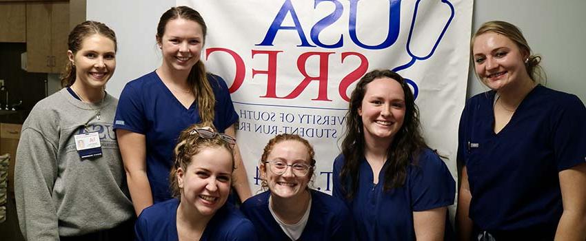 Audiology students pose with the USA SRFC banner after conducting an audiology and balancing screening at the clinic. 