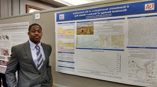 Male student standing in front of his Geology project.