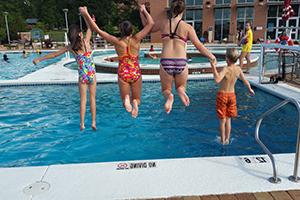 Kids jumping into Rec Center outdoor pool.