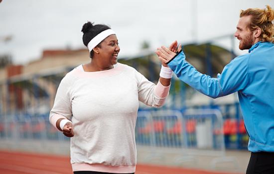 A male trainer high fiving a female on an outdoor track