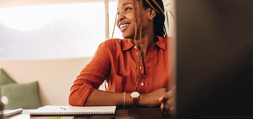 Woman in office working and smiling at desk.